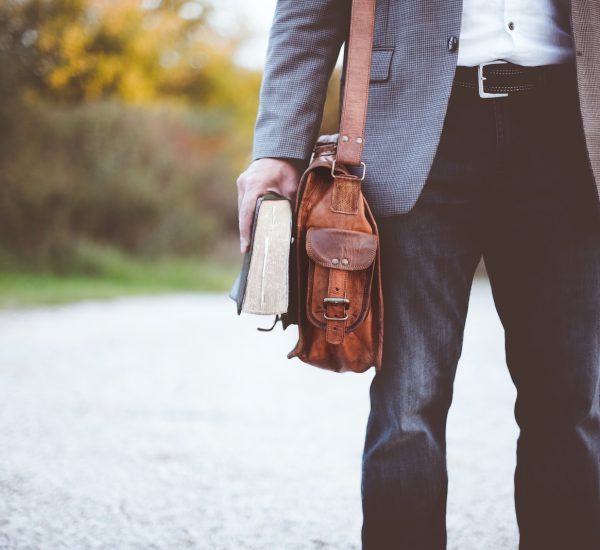 man holding book on road during daytime